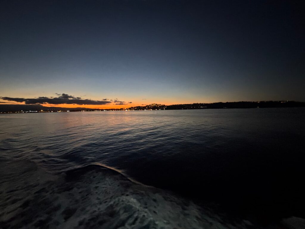 A large ferry docked at the harbor at dusk, preparing for the overnight crossing from Palermo to Naples during the Riding into the Lava tour."