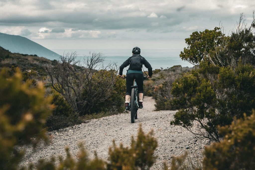 MTB rider tackling a scenic gravel trail in Lipari, with a breathtaking view of the Mediterranean Sea during the Riding into the Lava tour.