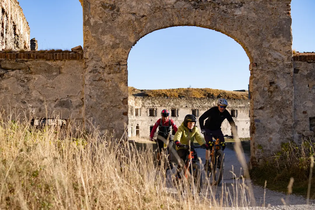 MTB riders passing through an ancient stone archway of a ruined military fort during the Bicknell Ciclovia tour with Trails Unlimited.