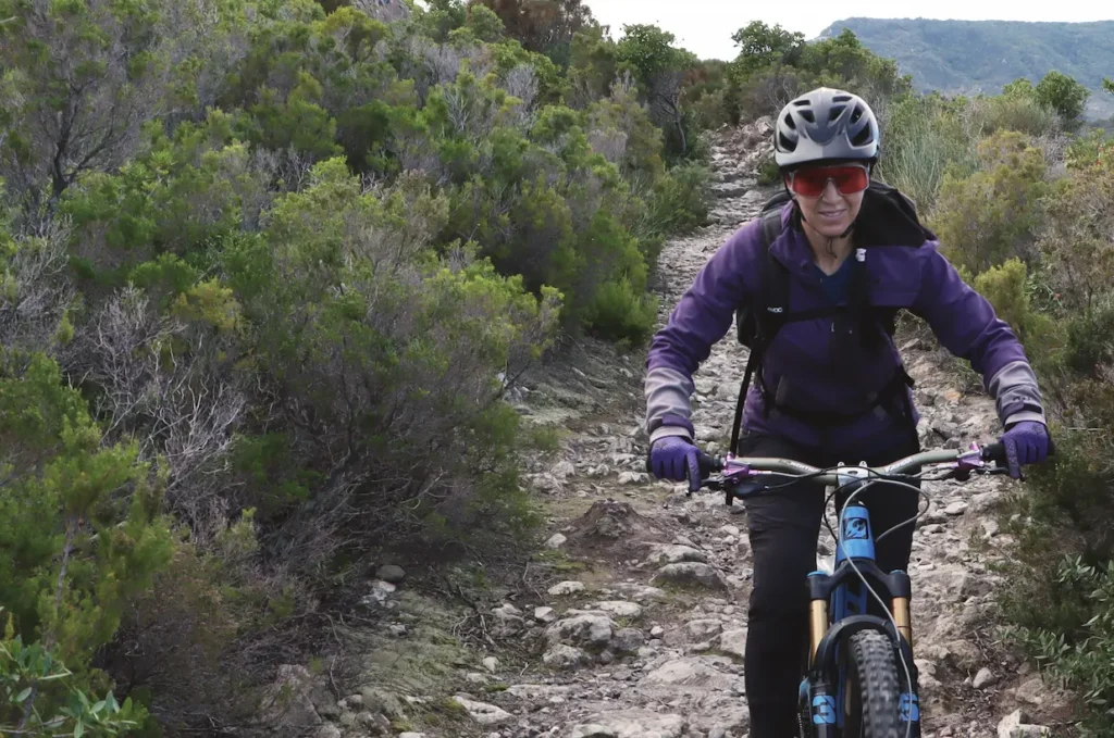 Trails Unlimited founder tackling a technical rock section on a mountain bike trail in Lipari, showcasing the rugged natural terrain of the Aeolian Islands.
