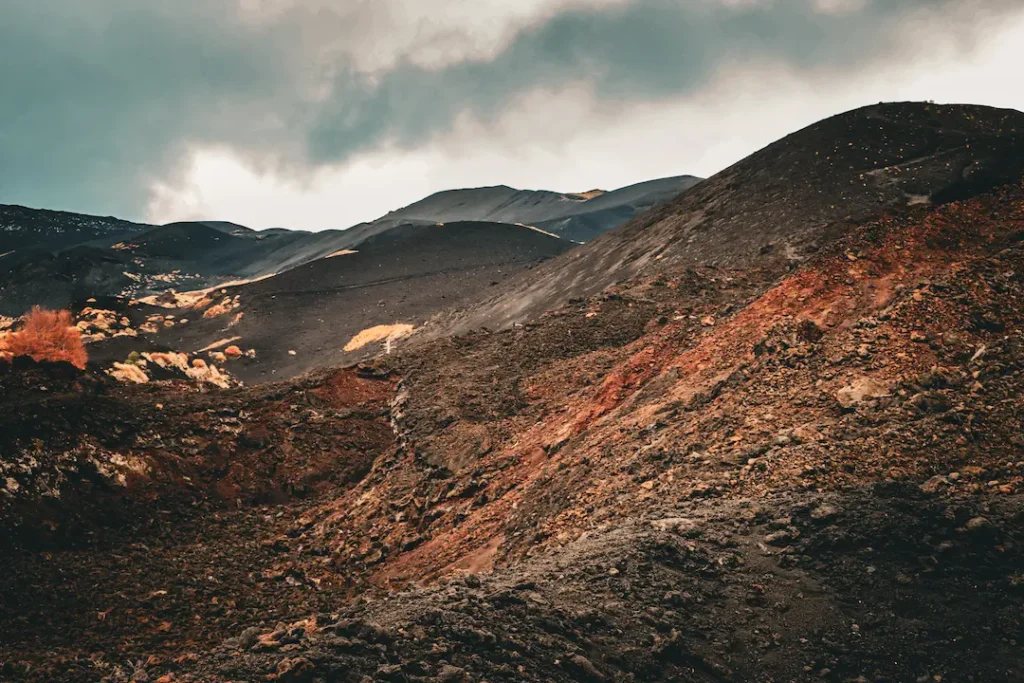 Panoramic view of the volcanic craters on Mount Etna's southern slope, showing the dark lava soil and rugged terrain during the Riding into the Lava MTB tour.