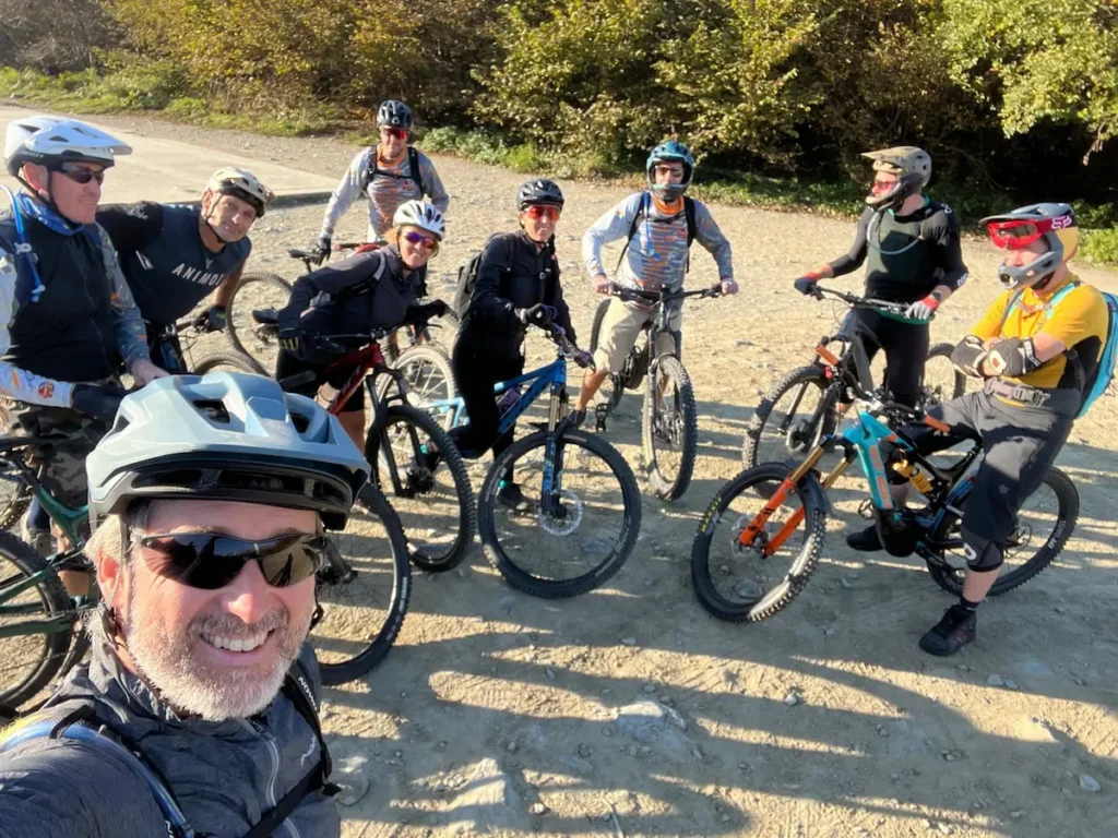 A happy group of mountain bikers smiling during a trail break in Finale Ligure, representing the Azur Club community spirit