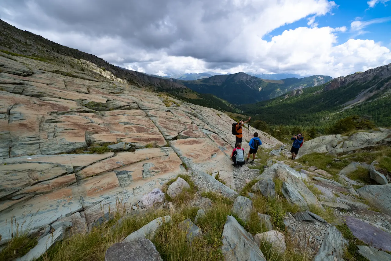Mountain bikers exploring the ancient rock engravings in the Vallée des Merveilles archaeological park during a guided MTB tour with Trails Unlimited.