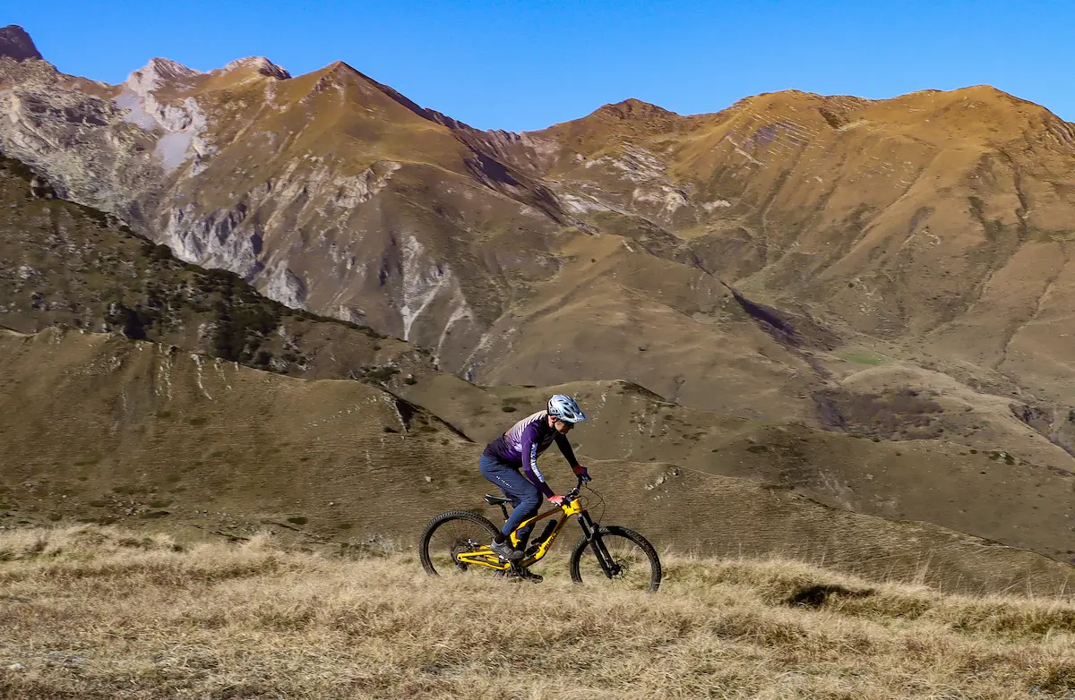 A scenic view of a Stefano Trails Unlimited guide on a winding trail amidst golden brown slopes, perfect for a chapter in the trail book.