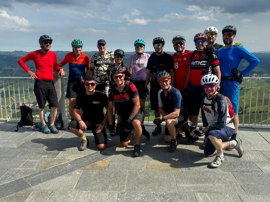 Group of cyclists posing at a scenic viewpoint during an EMTB tour in the Langhe vineyards.