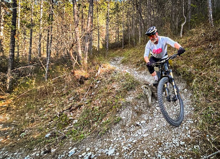 MTB tour in Western Liguria: rider on a rocky singletrack trail surrounded by pine trees.