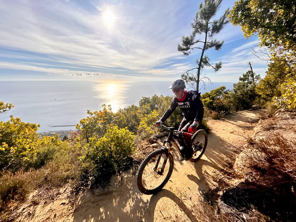 A mountain biker rides an enduro trail overlooking the Mediterranean Sea during a Sanremo MTB shuttle day tour on Monte Bignone.