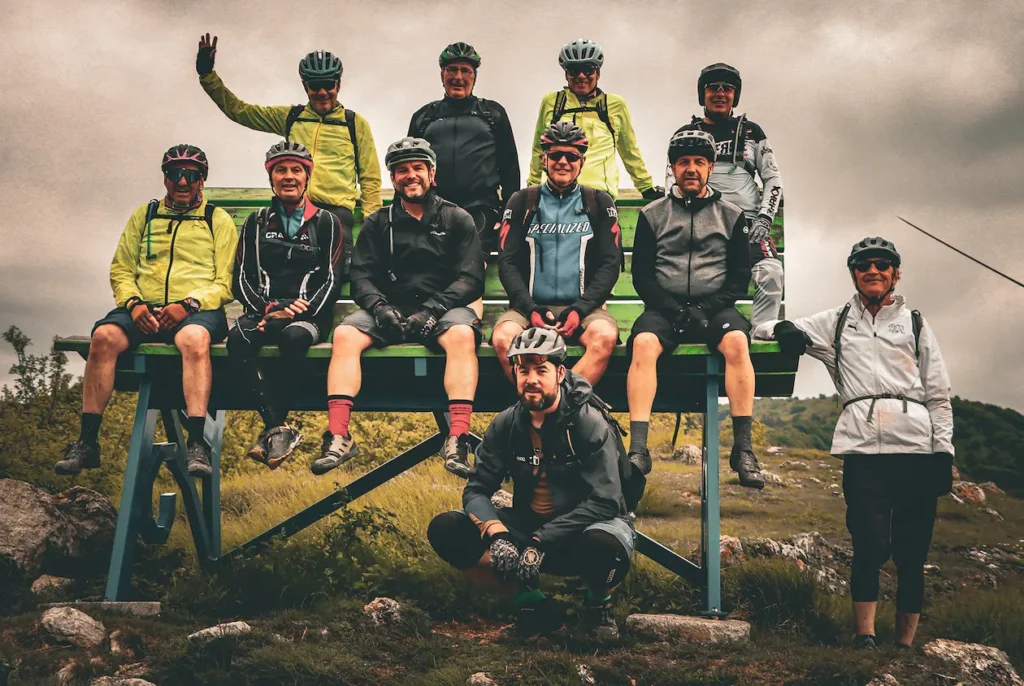 A happy group of mountain bikers smiling during a trail break in Finale Ligure, representing the Azur Club community spirit